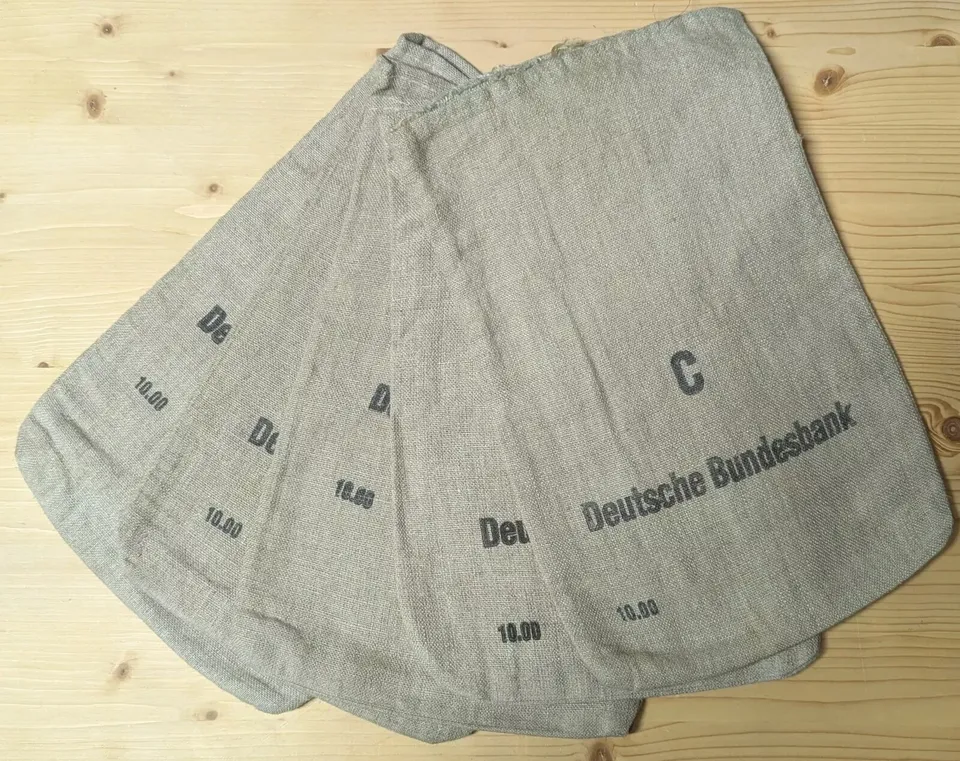 Mehrere originale Geldsäcke der Deutschen Bundesbank, Größe C, gefächert auf einem Holztisch, der Aufdruck ist gut lesbar.